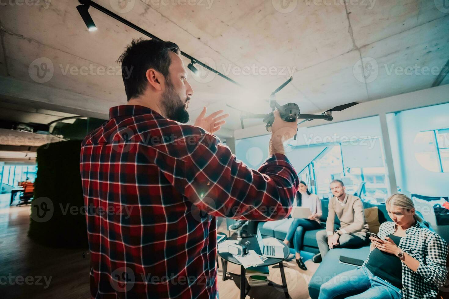 A bearded man in a modern office explaining to his young diverse team how a drone working photo