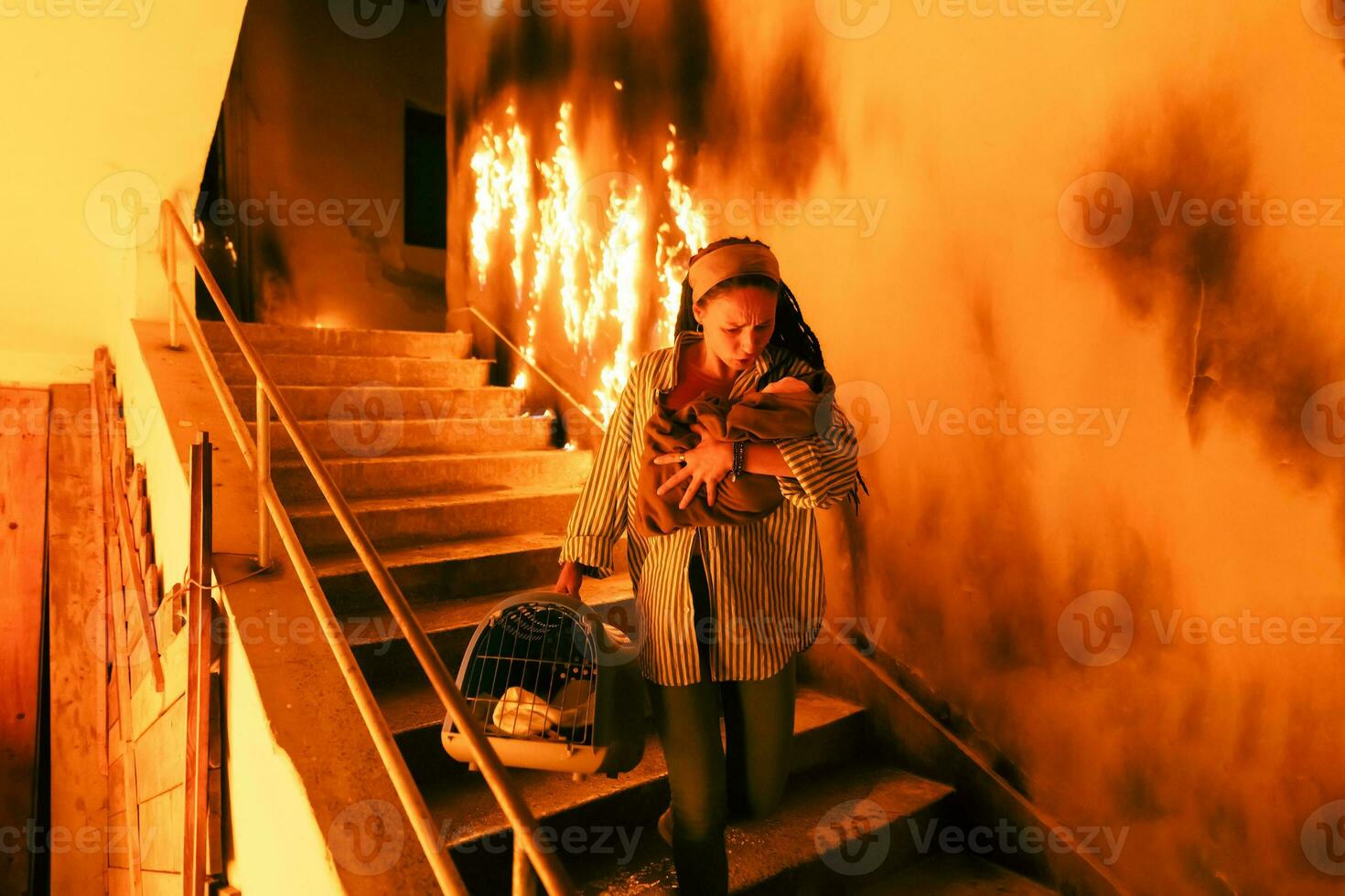 Brave Fireman Descends Stairs of a Burning Building and Holds Saved Girl in His Arms. Open fire and one Firefighter in the Background. photo