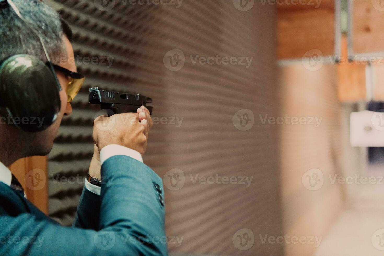 A man practices shooting a pistol in a shooting range while wearing protective headphones photo