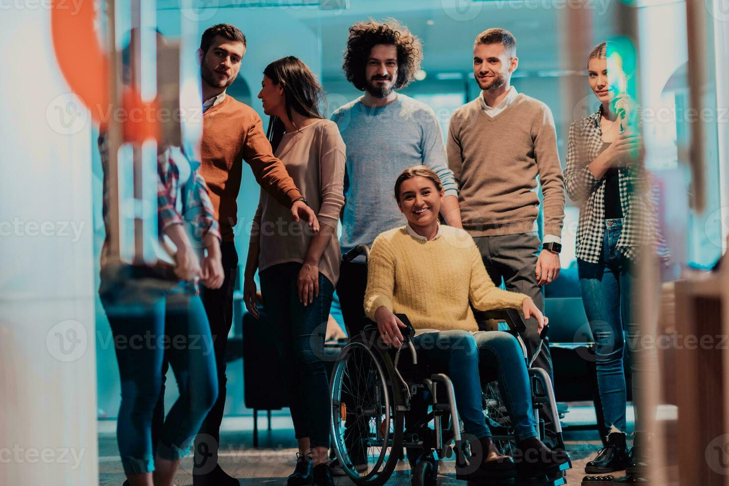 Businesswoman in a wheelchair on break in a modern office with her team in the background photo