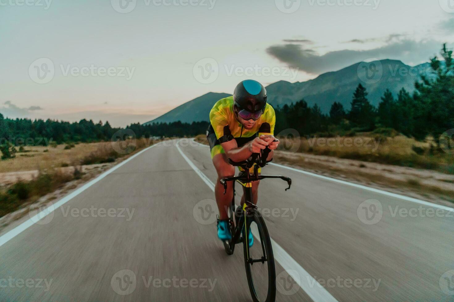noche conducir. lleno longitud retrato de un activo triatleta en ropa de deporte y con un protector casco montando un bicicleta en noche tiempo.. selectivo atención foto