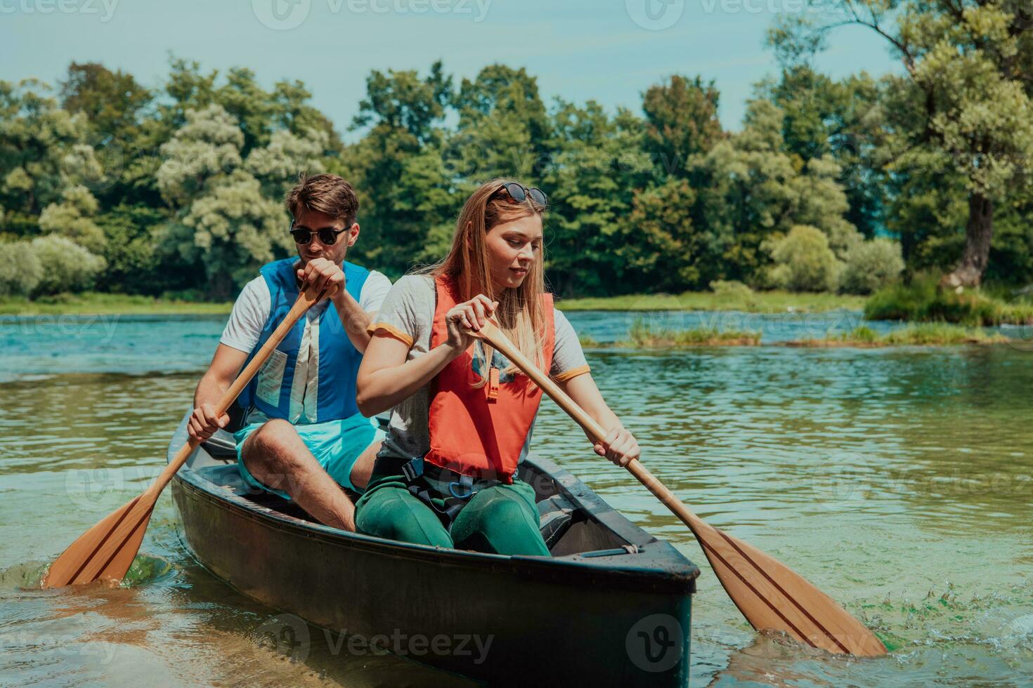 Couple adventurous explorer friends are canoeing in a wild river surrounded by the beautiful nature photo