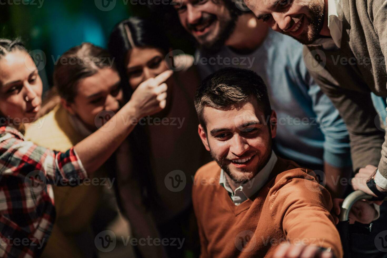 Diverse team of businessmen taking selfie photos on smartphone while in modern office