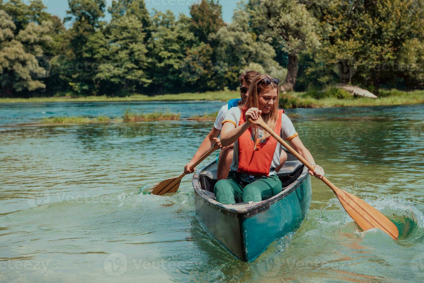 Couple adventurous explorer friends are canoeing in a wild river surrounded by the beautiful nature photo