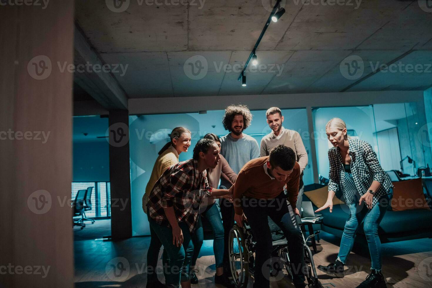 Colleagues help their friend in a wheelchair to take his first steps in a modern office after a serious illness photo