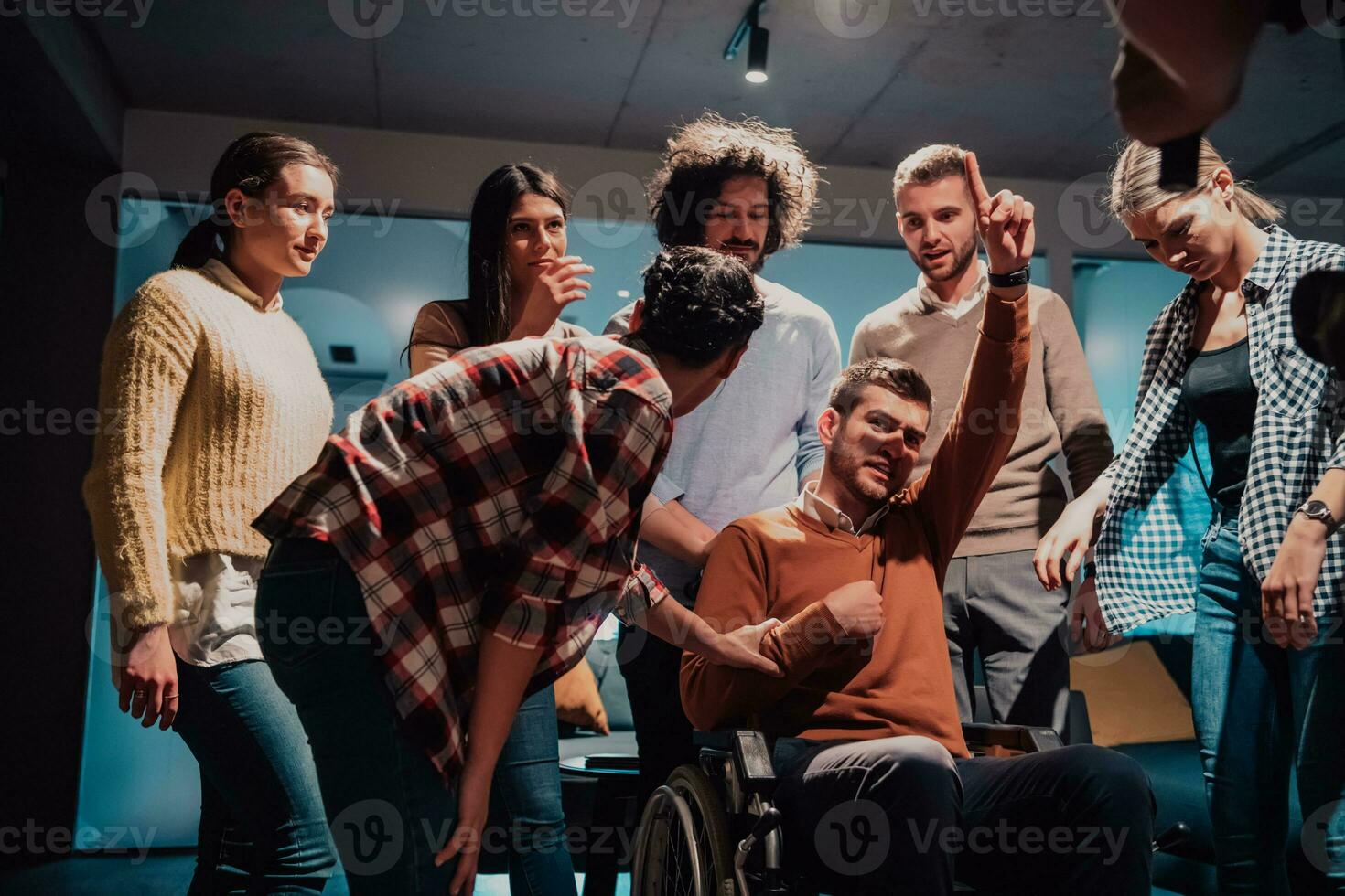 Colleagues help their friend in a wheelchair to take his first steps in a modern office after a serious illness photo