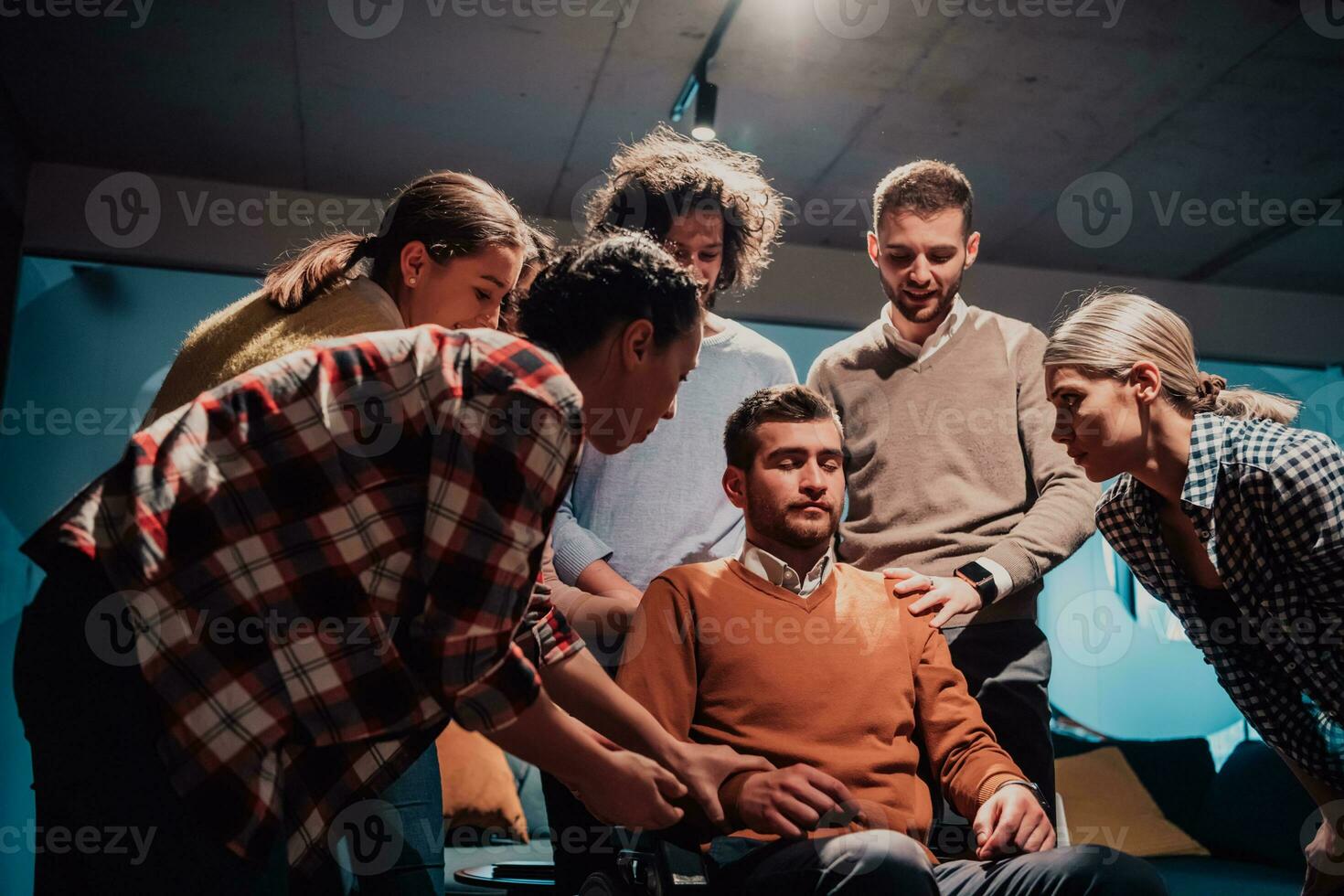 Colleagues help their friend in a wheelchair to take his first steps in a modern office after a serious illness photo