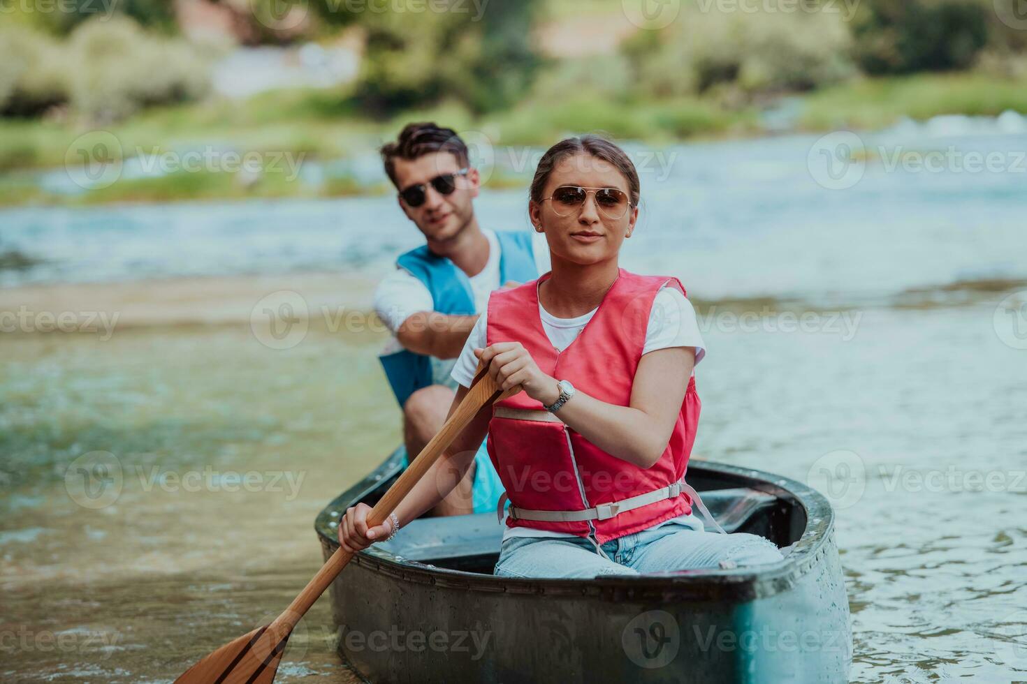 Couple adventurous explorer friends are canoeing in a wild river surrounded by the beautiful nature photo