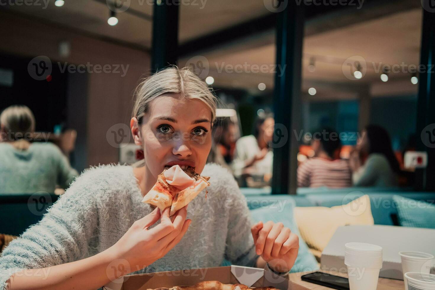 un moderno rubia comiendo Pizza en su oficina en un descanso desde trabajo foto