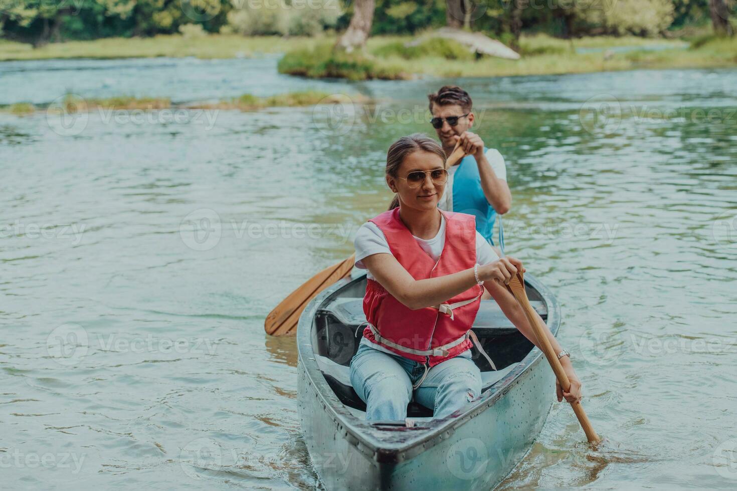 Couple adventurous explorer friends are canoeing in a wild river surrounded by the beautiful nature photo