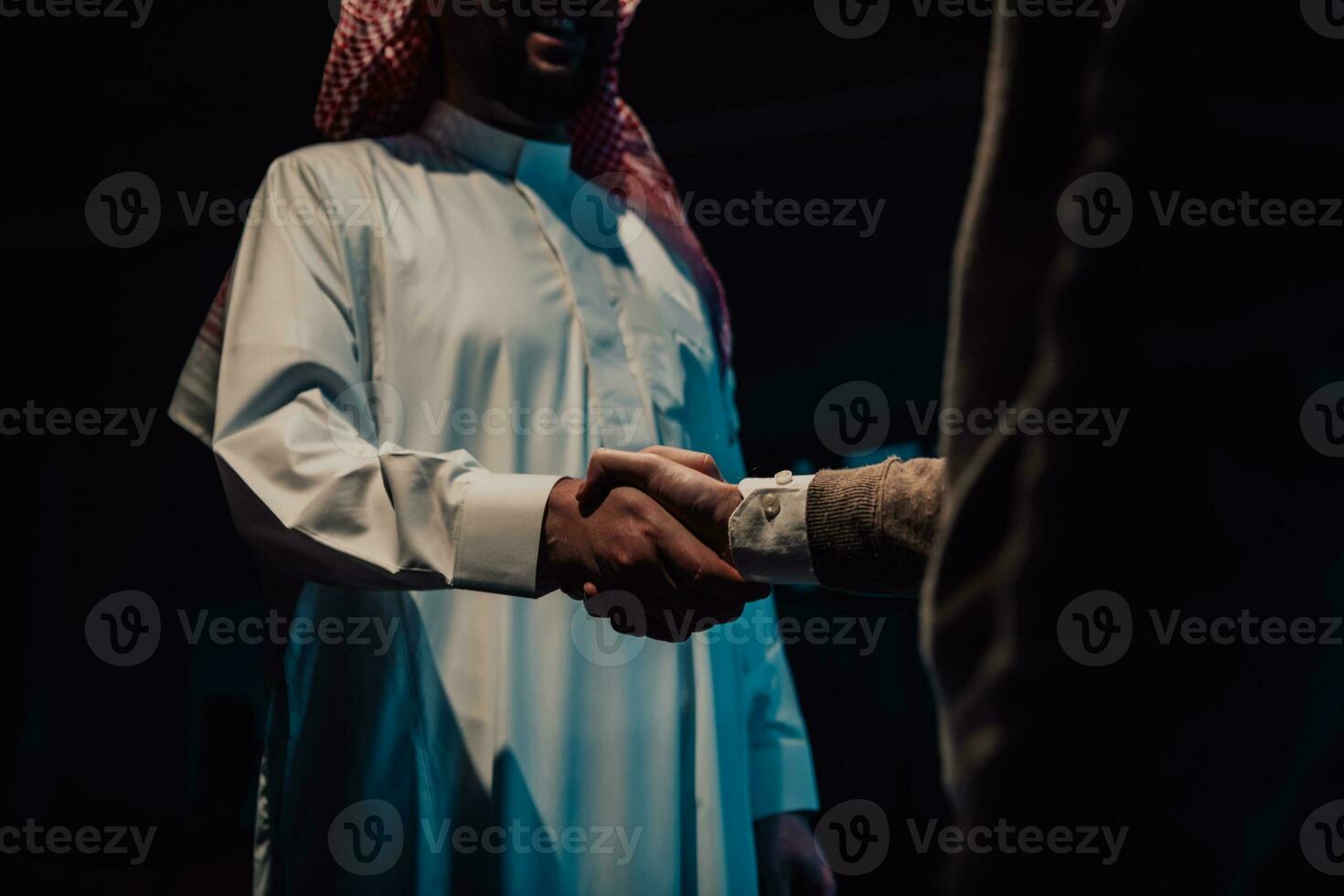 An elderly Arab man shaking hands with a businessman and ending a business meeting with successful business deals photo