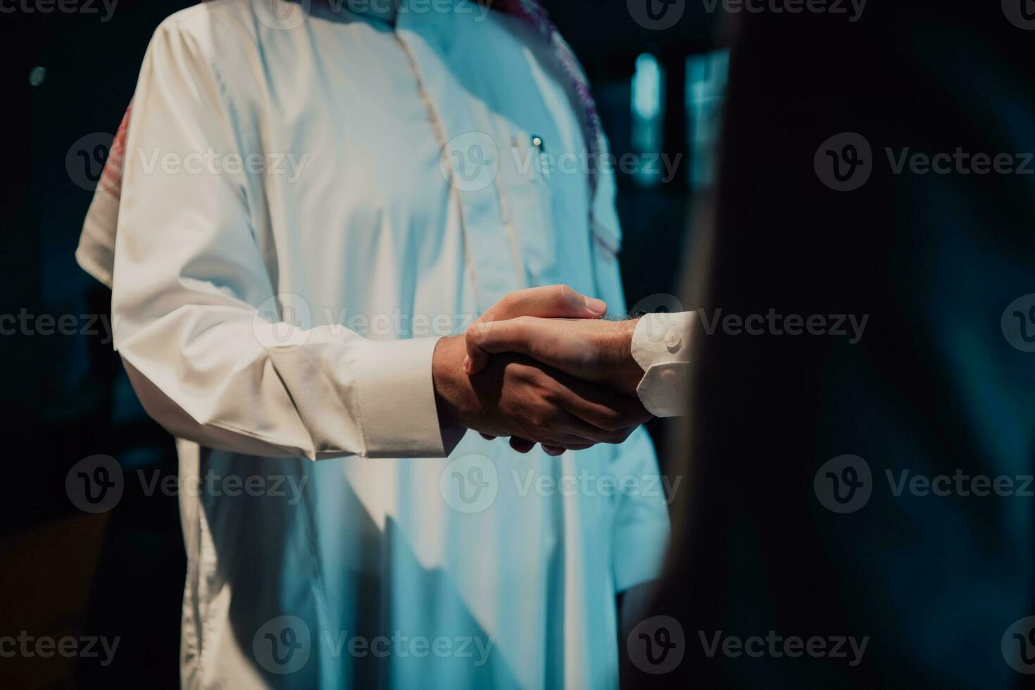 An elderly Arab man shaking hands with a businessman and ending a business meeting with successful business deals photo