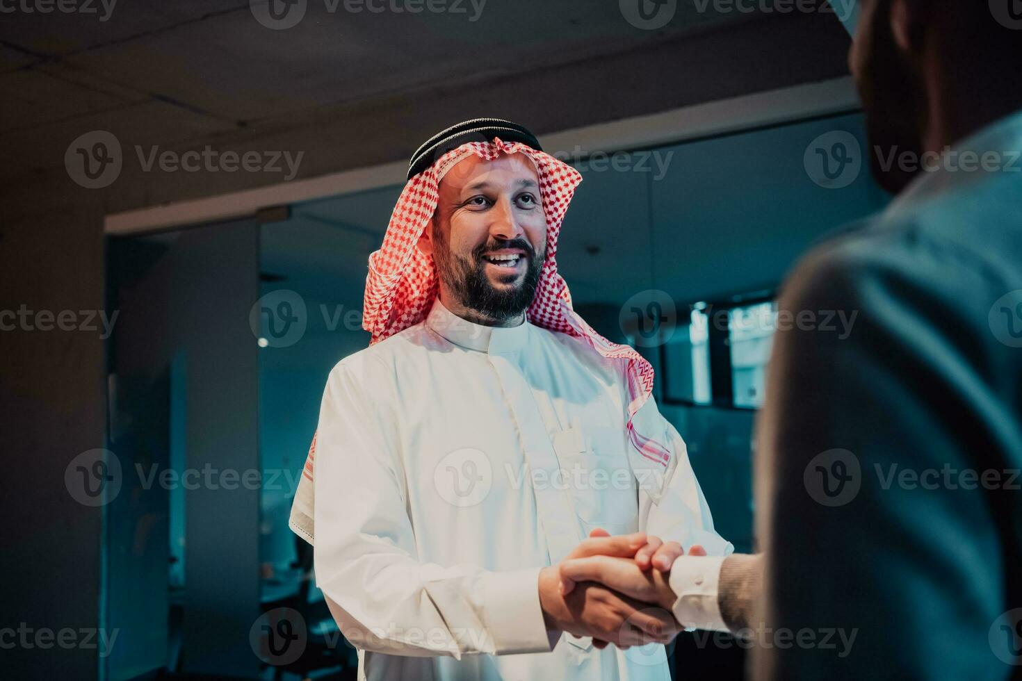 An elderly Arab man shaking hands with a businessman and ending a business meeting with successful business deals photo