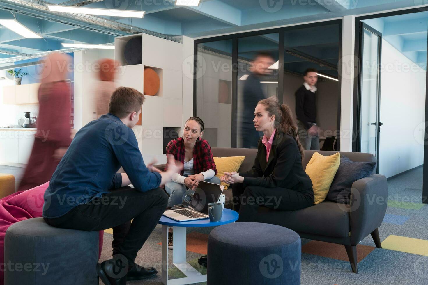 Multiethnic startup business team on meeting in a modern bright open space coworking office. Brainstorming, working on laptop. Group of coworkers walking around in motion blur. photo