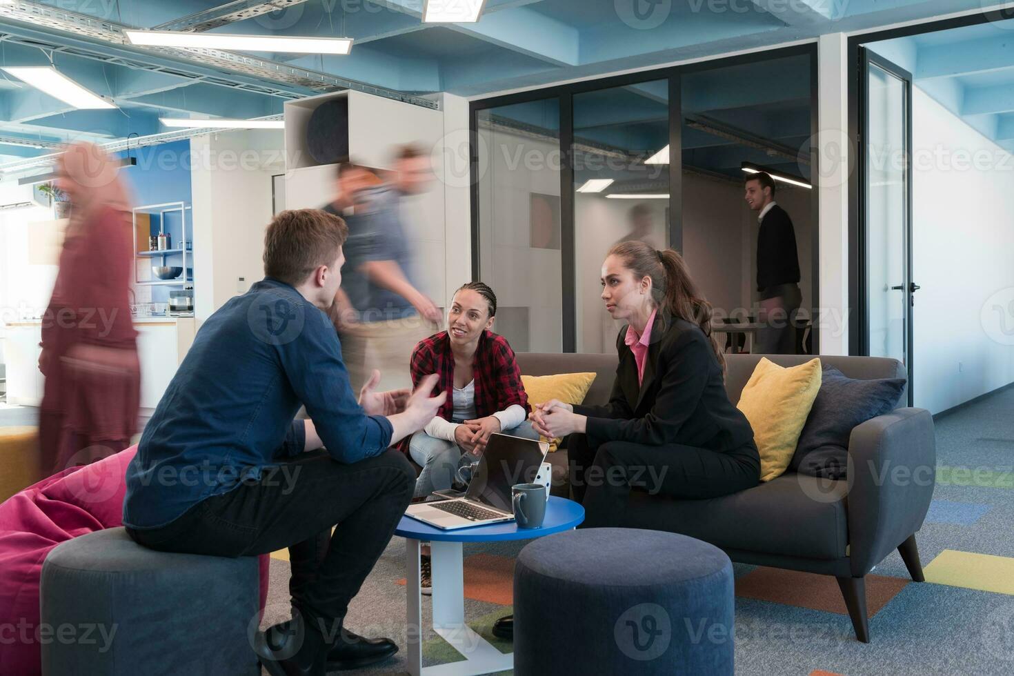 Multiethnic startup business team on meeting in a modern bright open space coworking office. Brainstorming, working on laptop. Group of coworkers walking around in motion blur. photo