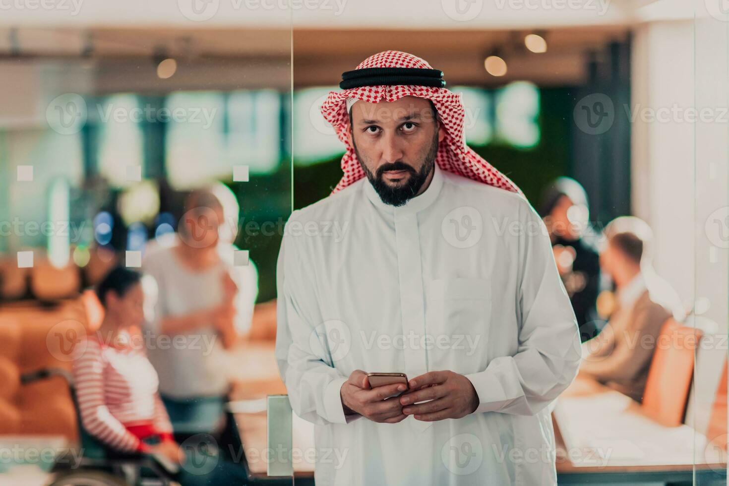 Middle eastern Arab businessman in the office speaking on smartphone in front of his team photo