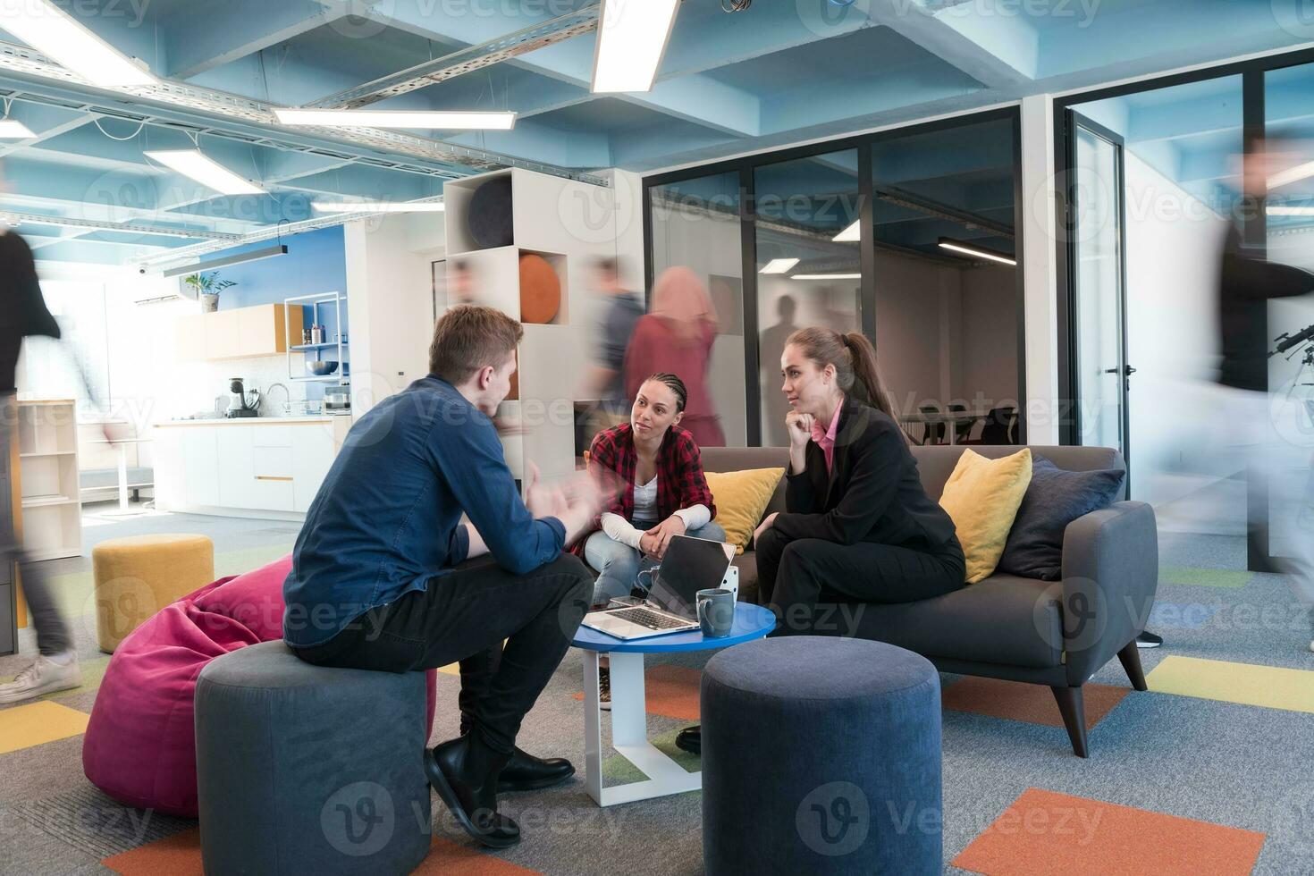 Multiethnic startup business team on meeting in a modern bright open space coworking office. Brainstorming, working on laptop. Group of coworkers walking around in motion blur. photo