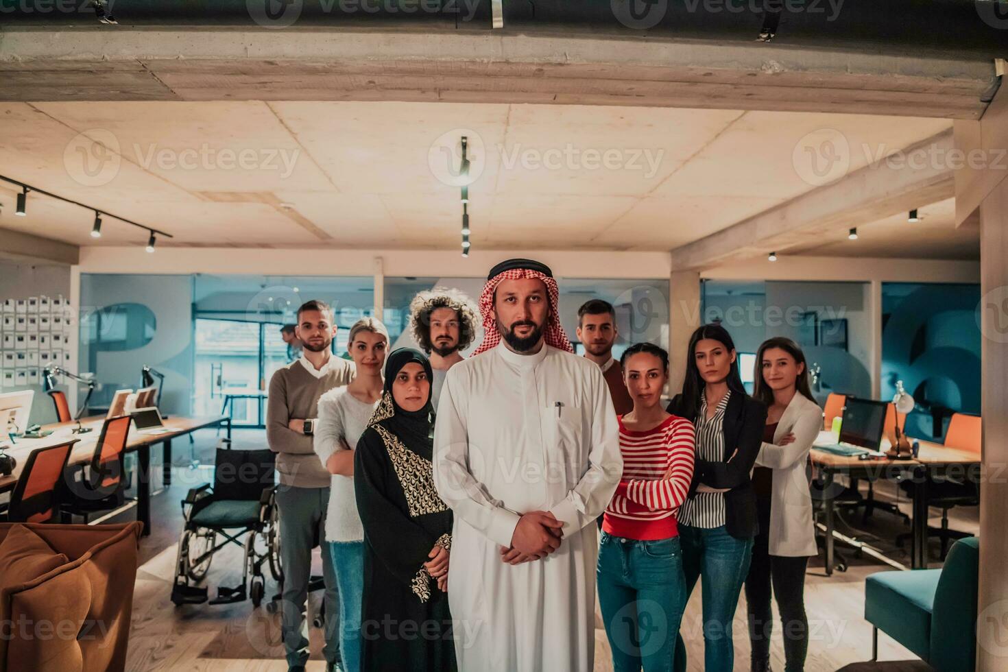 A diverse group of successful business people in a modern glass office stand together at the top with their Arab leader director photo