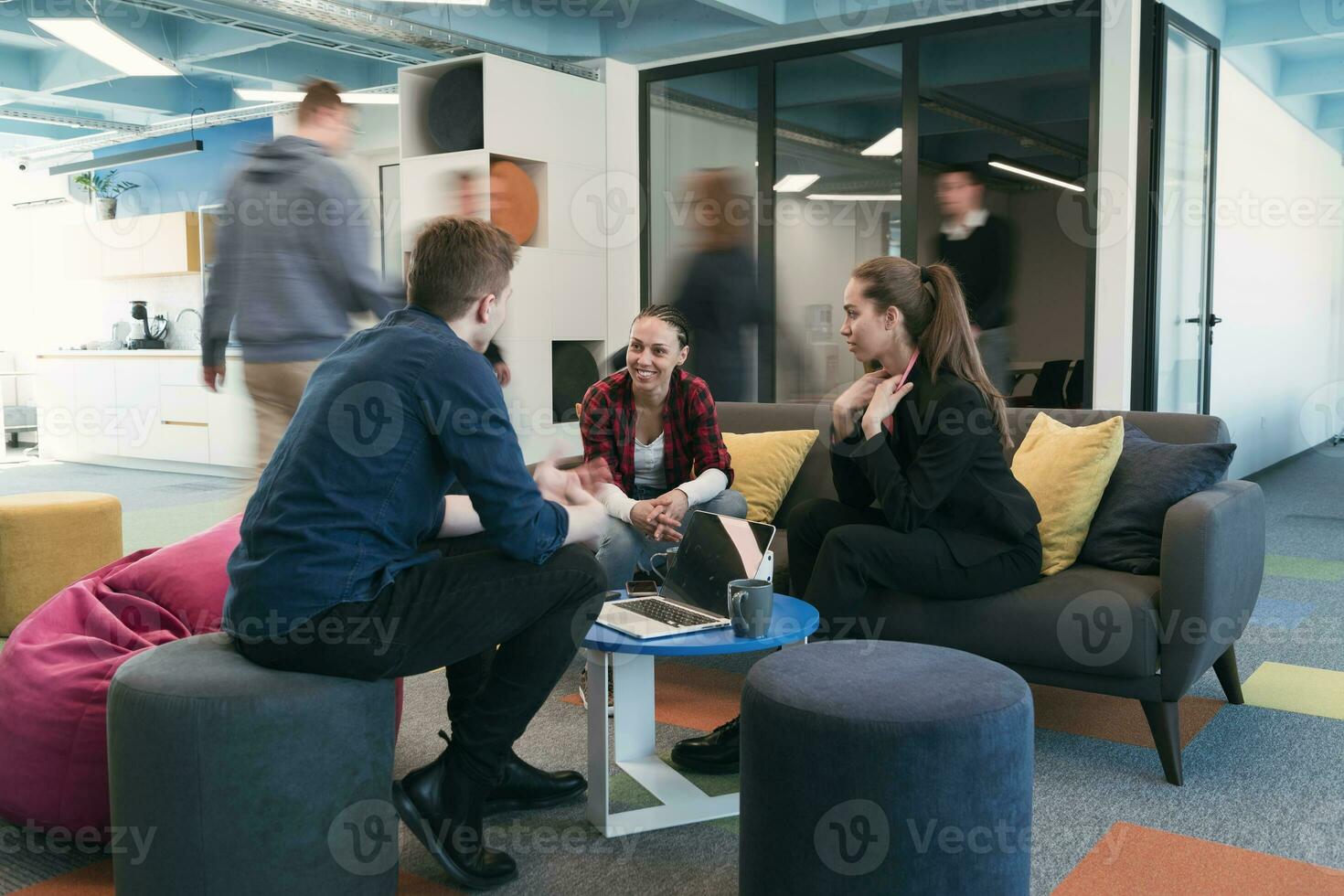Multiethnic startup business team on meeting in a modern bright open space coworking office. Brainstorming, working on laptop. Group of coworkers walking around in motion blur. photo