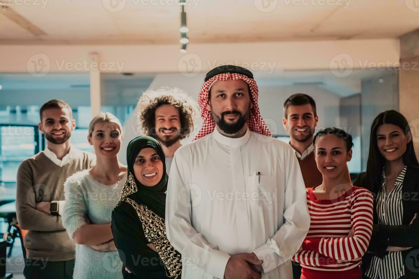 A diverse group of successful business people in a modern glass office stand together at the top with their Arab leader director photo