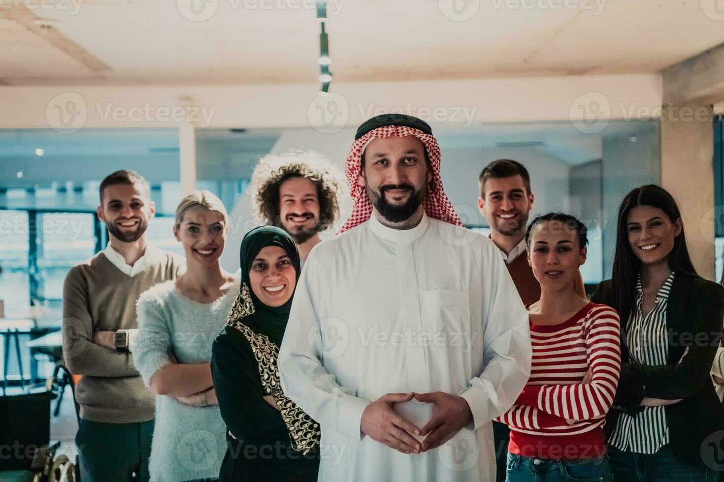 un diverso grupo de exitoso negocio personas en un moderno vaso oficina estar juntos a el parte superior con su árabe líder director foto