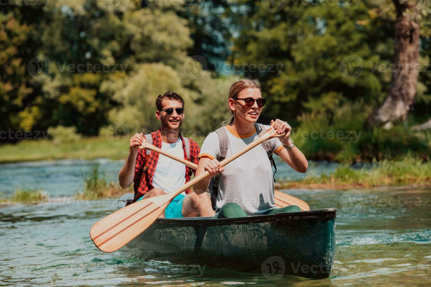 Couple adventurous explorer friends are canoeing in a wild river surrounded by the beautiful nature photo