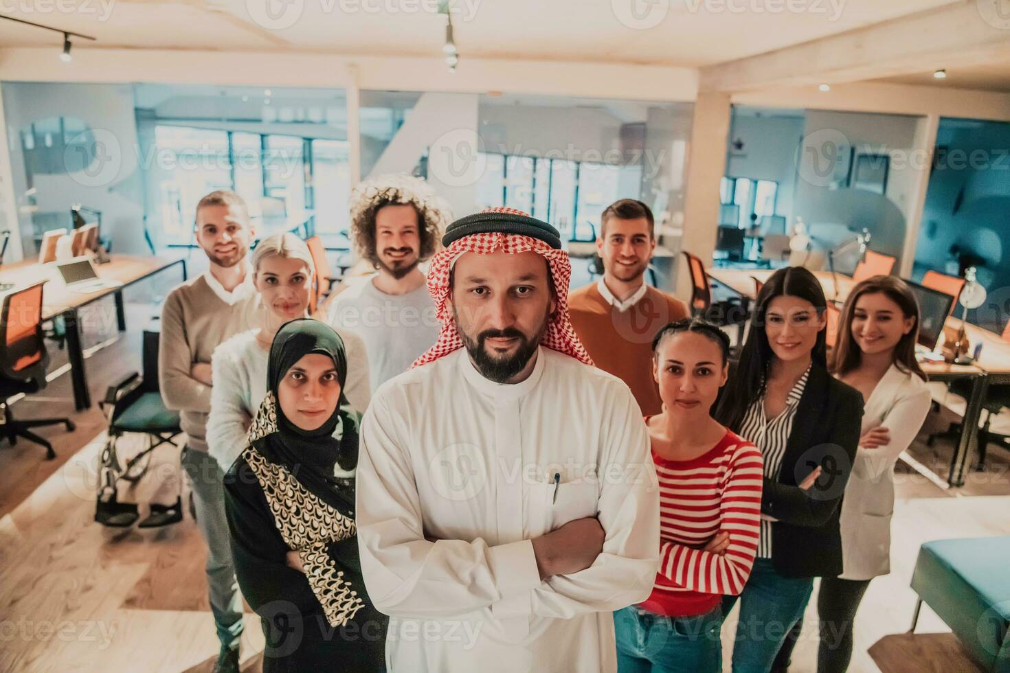 A diverse group of successful business people in a modern glass office stand together at the top with their Arab leader director photo