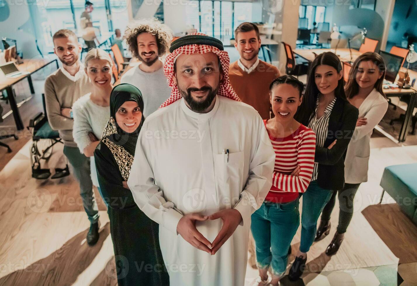 A diverse group of successful business people in a modern glass office stand together at the top with their Arab leader director photo