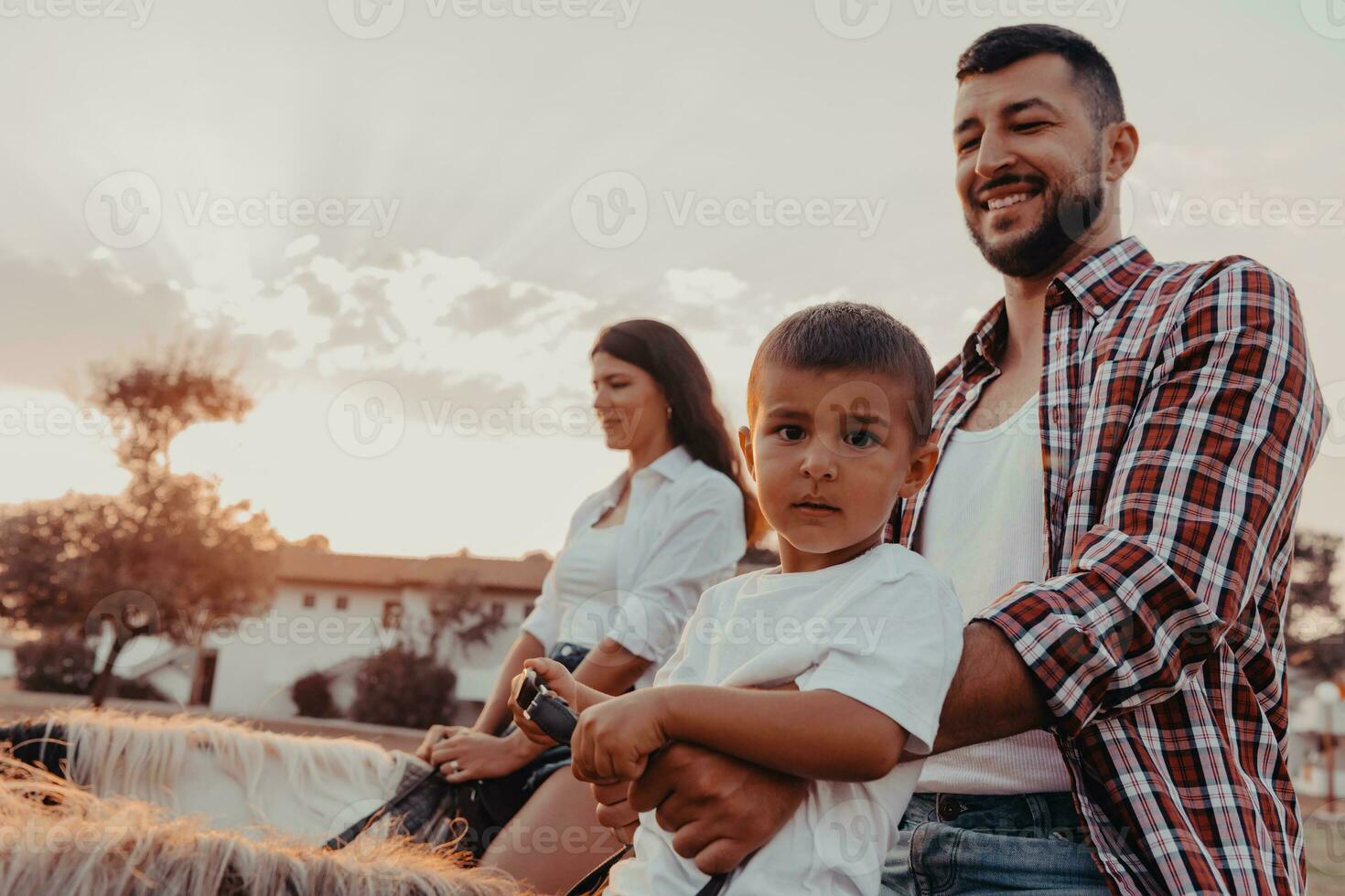 The family spends time with their children while riding horses together on a sandy beach. Selective focus photo