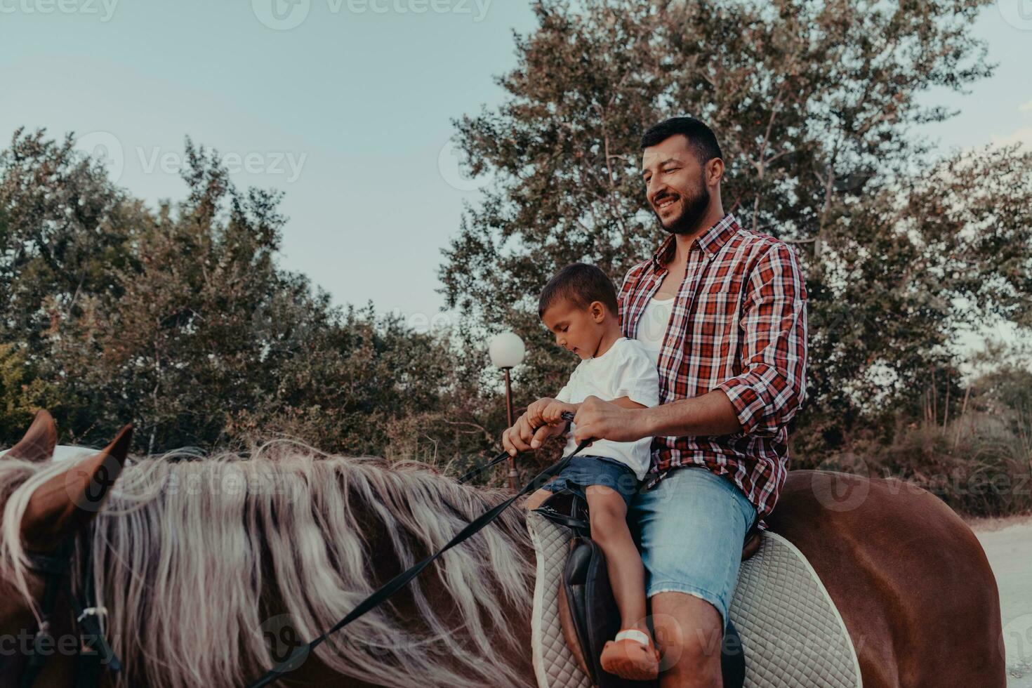 Father and son enjoy riding horses together by the sea. Selective focus photo