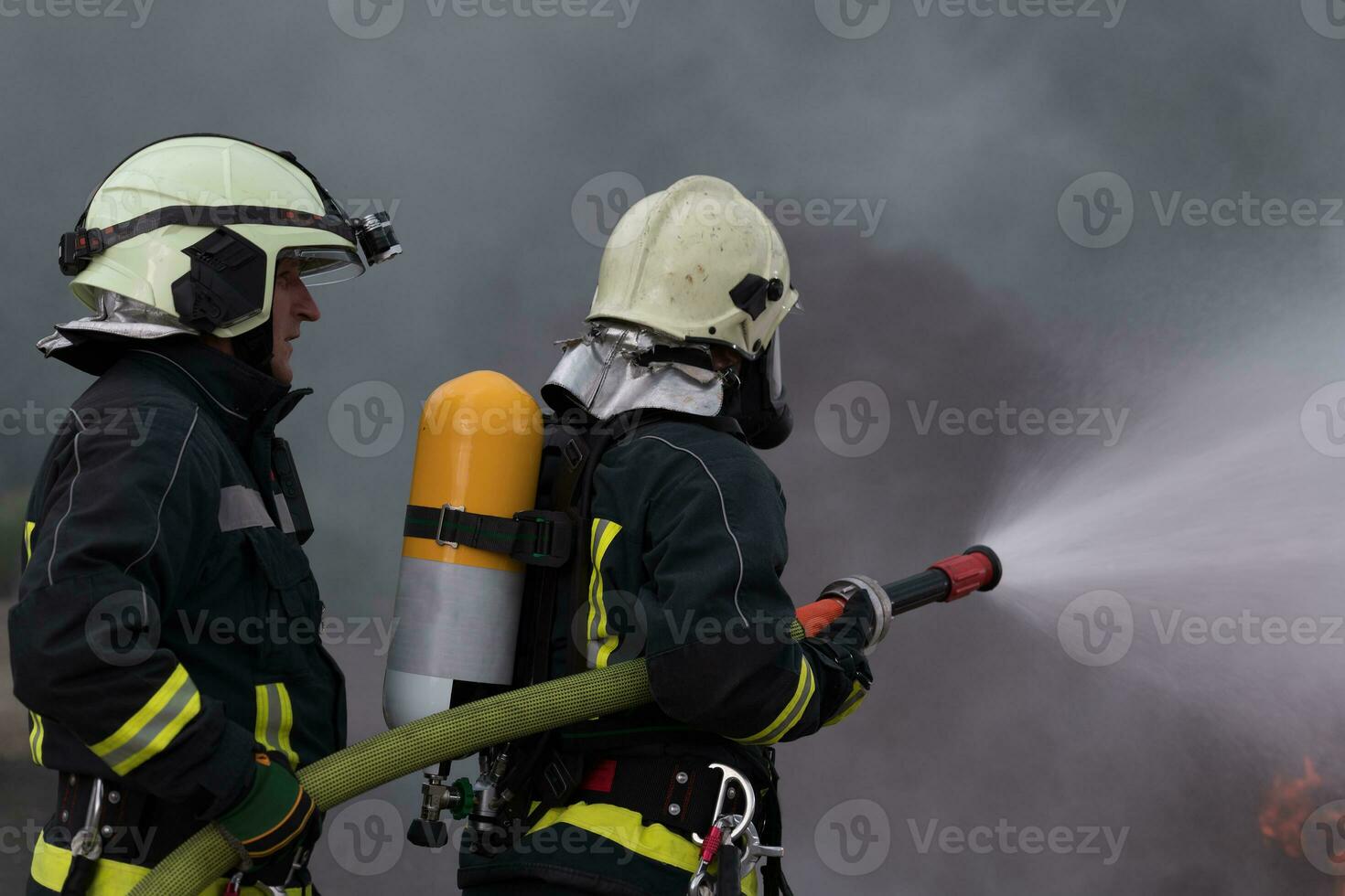 Firefighters using water fog type fire extinguisher to fighting with the fire flame to control fire not to spreading out. Firefighter industrial and public safety concept. photo