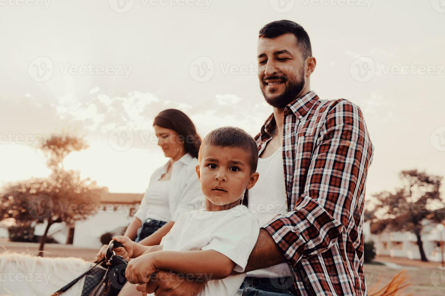 The family spends time with their children while riding horses together on a sandy beach. Selective focus photo