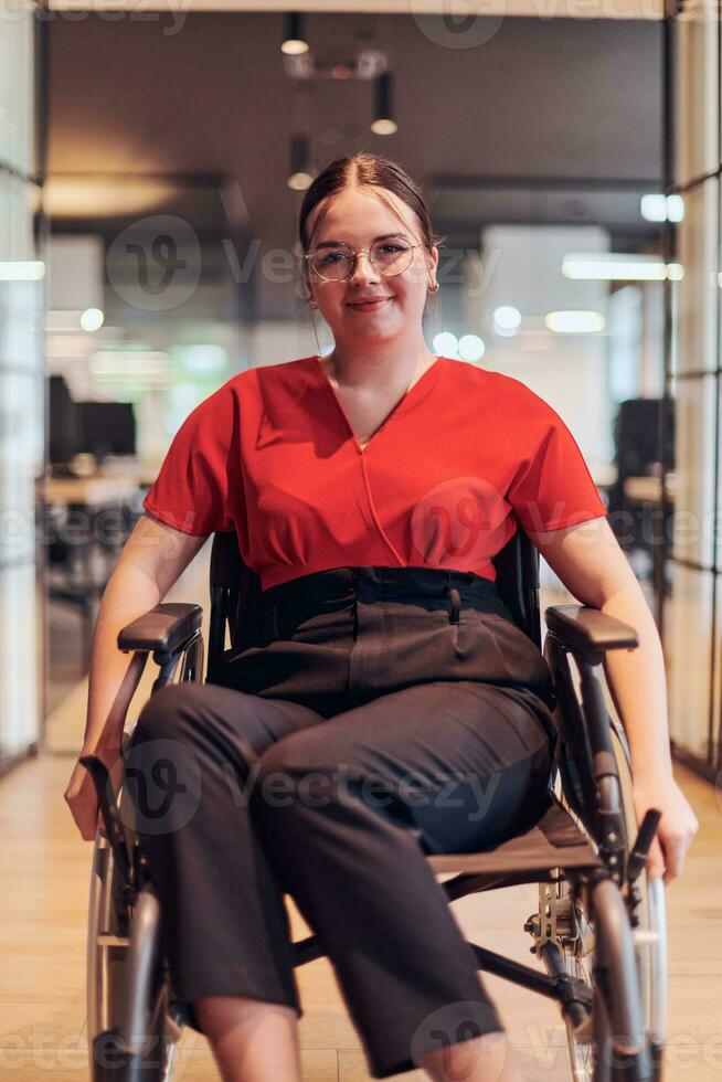 A modern young businesswoman in a wheelchair is surrounded by an inclusive workspace with glass-walled offices, embodying determination and innovation in the business world photo