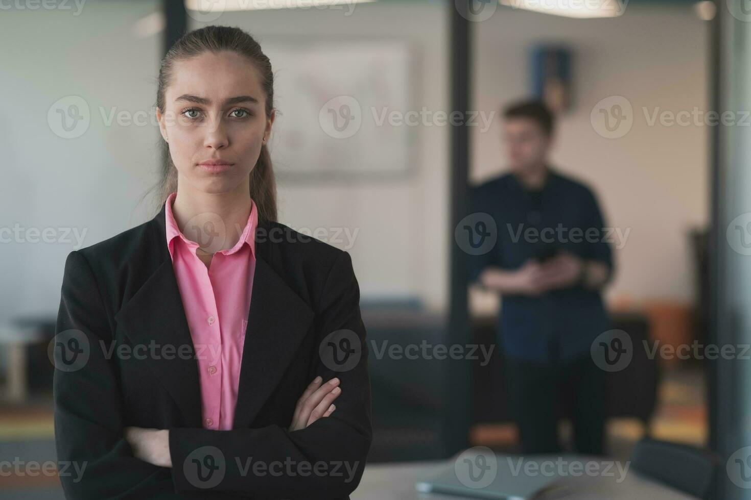 Portrait of young smiling business woman in creative open space coworking startup office. Successful businesswoman standing in office with copyspace. Coworkers working in background. photo