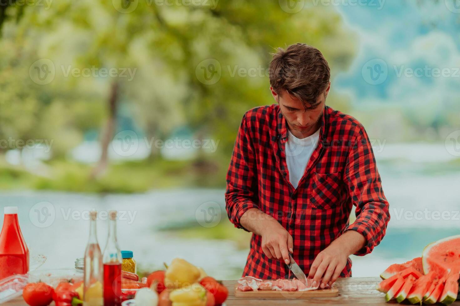 A man preparing a delicious dinner for his friends who are having fun by the river in nature photo