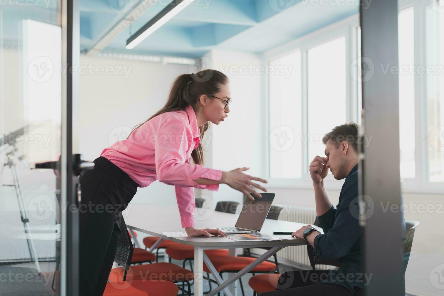 Emotional couple of young colleagues arguing in modern office. Business woman shouting at her sad man assistant, copy space, side view photo