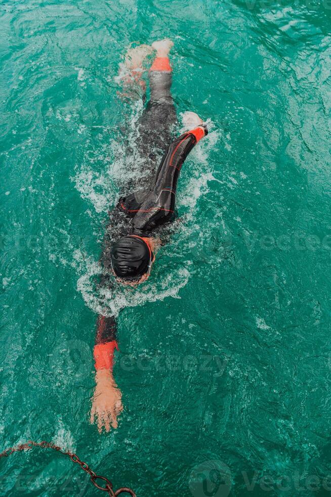 A triathlete in a professional swimming suit trains on the river while preparing for Olympic swimming photo