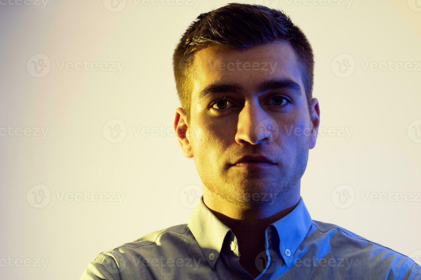 A man in a shirt poses on a dark multicolored neon background photo