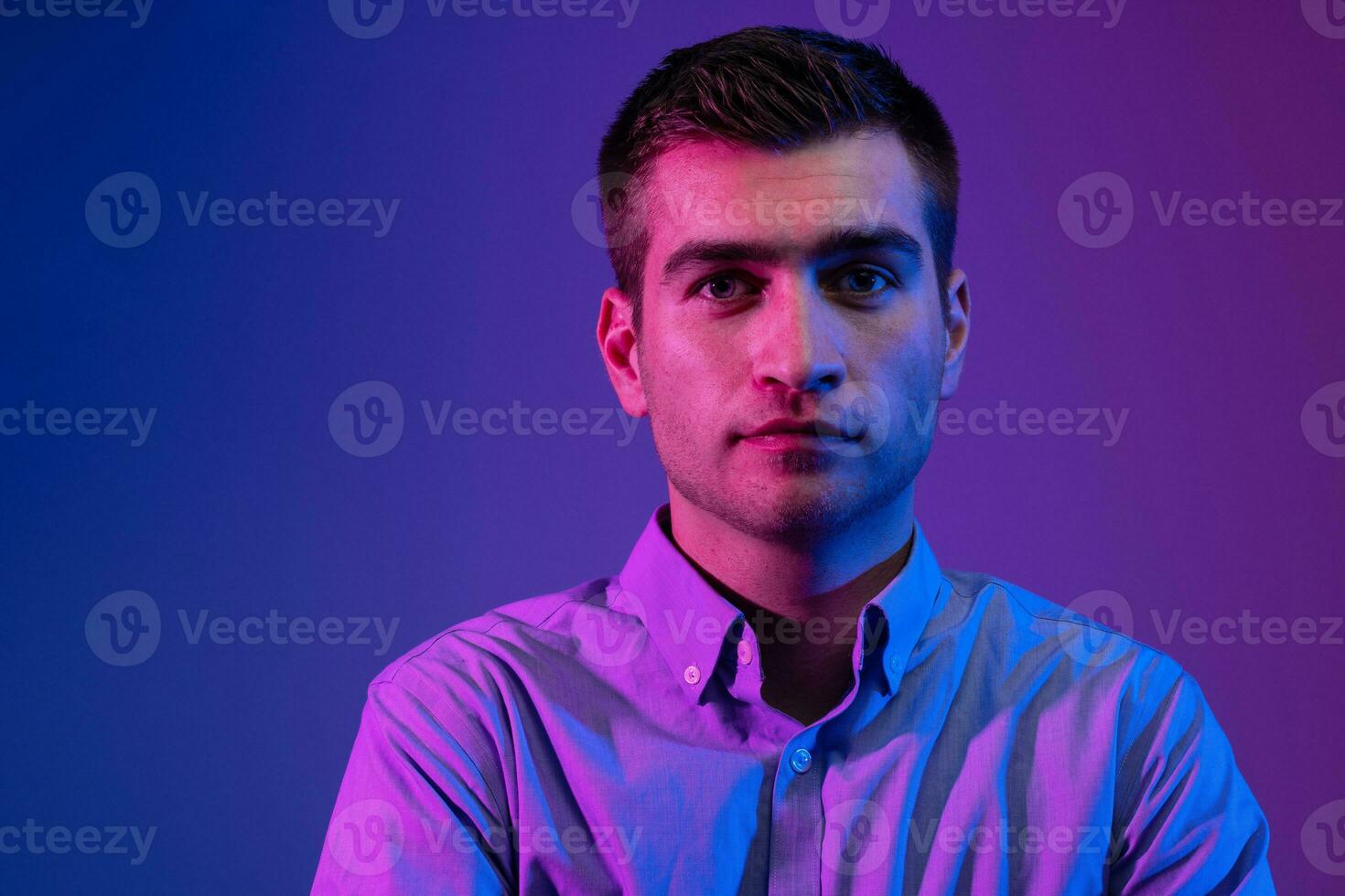 A man in a shirt poses on a dark multicolored neon background photo