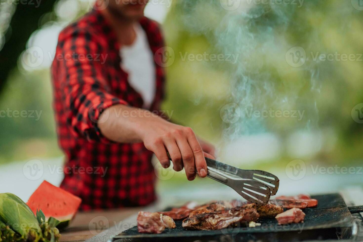 A man preparing a delicious dinner for his friends who are having fun by the river in nature photo