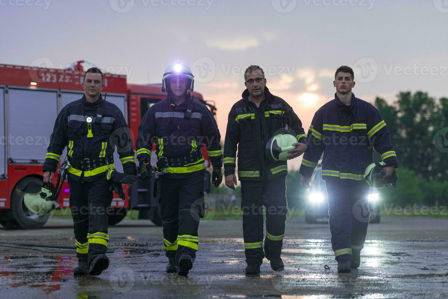 Brave Firefighters Team Walking to the Camera. In Background Paramedics and Firemen Rescue Team Fight Fire in Car Accident, Insurance and Save Peoples Lives concept. photo