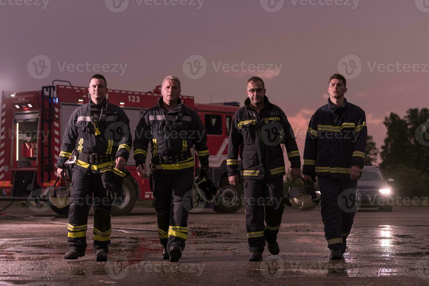 Brave Firefighters Team Walking to the Camera. In Background Paramedics and Firemen Rescue Team Fight Fire in Car Accident, Insurance and Save Peoples Lives concept. photo