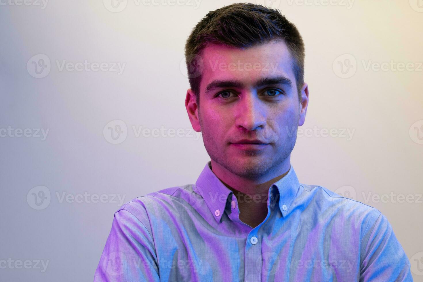 A man in a shirt poses on a dark multicolored neon background photo