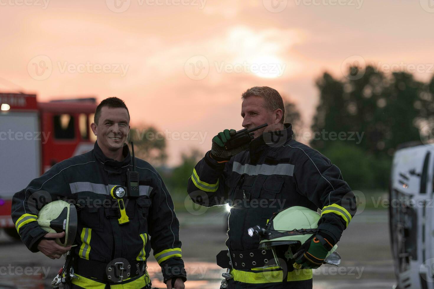 fireman using walkie talkie at rescue action fire truck and fireman's team in background. photo