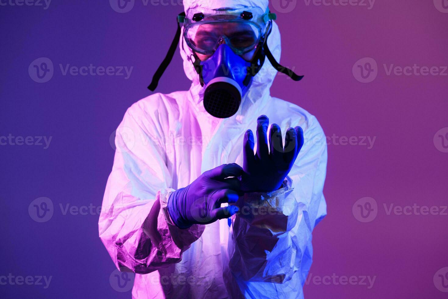 Coronavirus covid-19 pandemic. Doctor scientist wearing protective biological suit and mask due to global healthcare epidemic warning and danger background in blue and pink neon lights background. photo