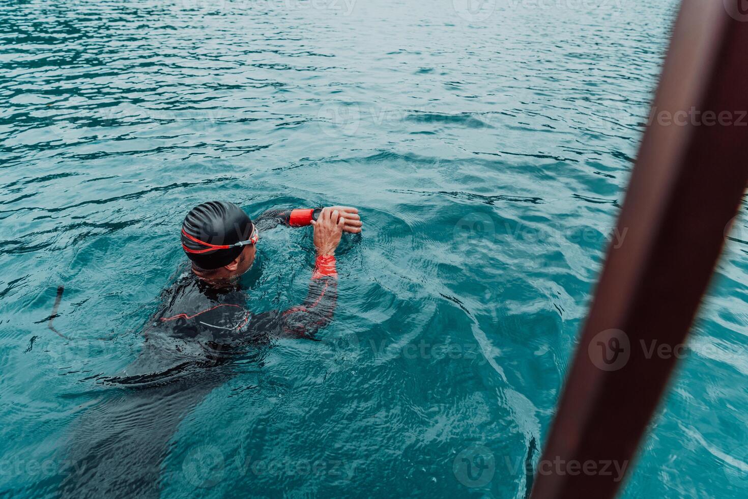 A triathlete in a professional swimming suit trains on the river while preparing for Olympic swimming photo