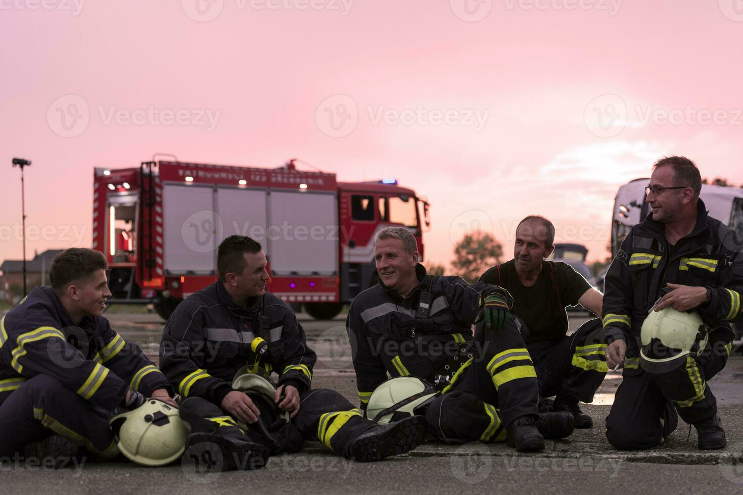 Brave Firefighters Team Walking to the Camera. In Background Paramedics and Firemen Rescue Team Fight Fire in Car Accident, Insurance and Save Peoples Lives concept. photo