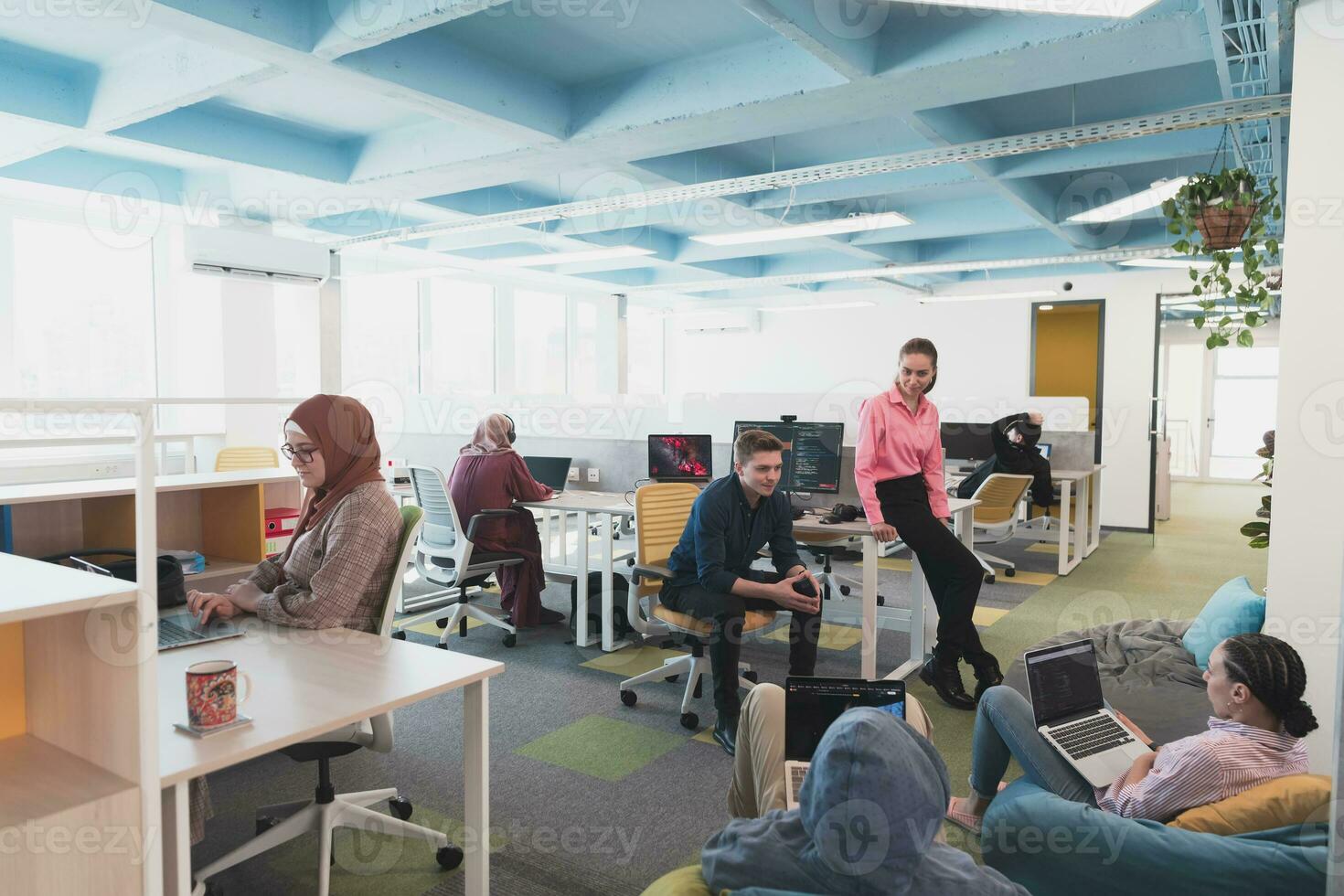Portrait of young smiling business woman in creative open space coworking startup office. Successful businesswoman standing in office with copyspace. Coworkers working in background. photo