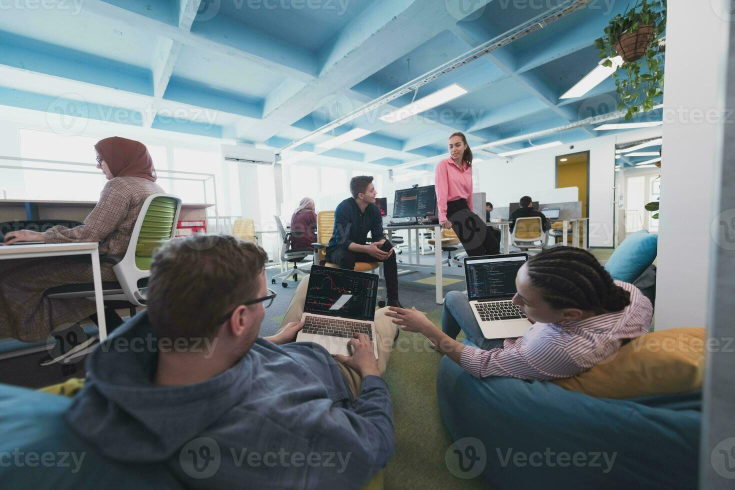 Portrait of young smiling business woman in creative open space coworking startup office. Successful businesswoman standing in office with copyspace. Coworkers working in background. photo