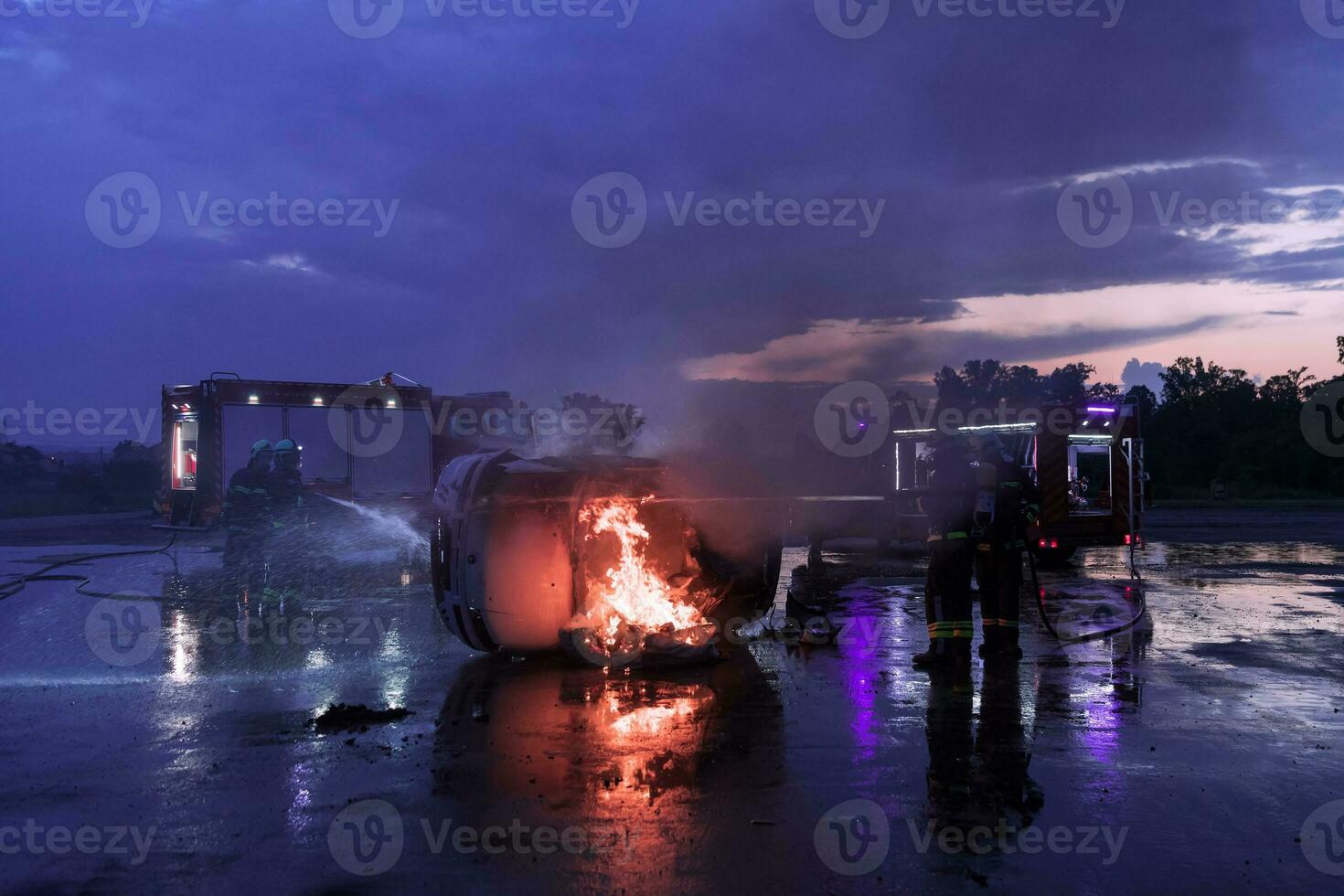 Firefighters using water fire extinguisher to fighting with the fire flame in car accident. Firefighter industrial and public safety concept rescue in night. photo